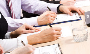 Dedicated group of employment law professionals write on clipboards in a meeting.